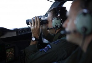 Wing Commander Rob Shearer looks through binoculars on the flight deck of a Royal New Zealand Air Force P-3K2 Orion aircraft during a search for the missing Malaysian Airlines flight MH370 over the southern Indian Ocean, March 29, 2014.  Courtesy REUTERS/Jason Reed