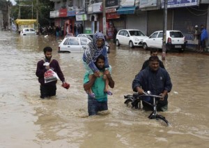 A Kashmiri man evacuates an elderly woman to a higher ground at a flooded road in Srinagar September 7, 2014.  REUTERS/Danish Ismail