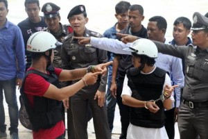 Two workers from Myanmar (wearing helmets and handcuffs), suspected of killing two British tourists on the island of Koh Tao last month, stand near Thai police officers during a re-enactment of the alleged crime, where the bodies of the tourists were found on Koh Tao island October 3, 2014. REUTERS/Stringer