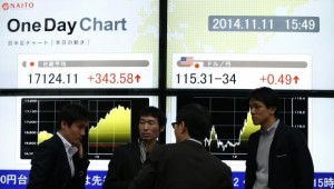 Pedestrians stand in front of an electronic board showing Japan's Nikkei average and the exchange rates between the Japanese yen and the U.S. dollar, outside a brokerage in Tokyo