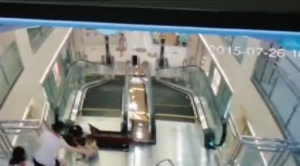 The  woman falls in a gap on the escalator platform but was able to save her son.  (Photo grabbed from surveillance video provided by China state television, CCTV)