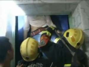 Firefighters try to rescue a trapped woman in the elevator in a residential compound in east China.  (Photo grabbed from China Central Television video) 