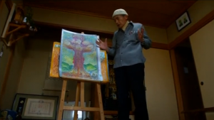 Retired school teacher and atomic bomb survivor, 76-year-old Fumiaki Kajiya, putting up a drawing about atomic bombing.  (Photo grabbed from Reuters video)