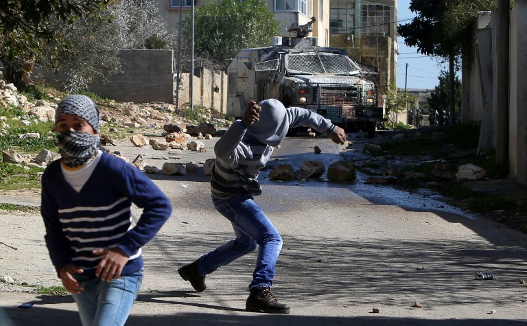 Palestinian protesters hurls rocks during clashes with Israeli soldiers following a demonstration against the expropriation of Palestinian land by Israel on February 12, 2016 in the village of Kfar Qaddum, near Nablus in the occupied West Bank. / AFP / JAAFAR ASHTIYEH