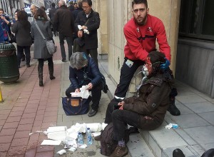 A private security guard helps a wounded women outside the Maalbeek metro station in Brussels on March 22, 2016 after a blast at this station located near the EU institutions./ AFP / Michael VILLA