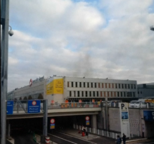 A still photograph uploaded to a social media website purports to shows black smoke rising from a building at Brussels airport following two explosions at the departures terminal. (Courtesy Reuters)