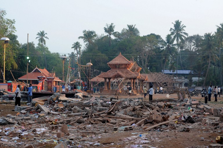 Indian bystanders gather among debris and building wreckage of The Puttingal Devi Temple in Paravur some 60kms north-west of Thiruvananthapuram on April 11, 2016.  More than 100 people have died and 350 injured when fireworks meant to be lit for festivities caught fire and exploded near the temple where thousands of people had gathered to witness the festivities on the early hours of April 10. / AFP PHOTO / MANJUNATH KIRAN