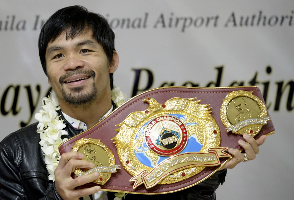 Filipino boxer Manny Pacquiao holds his championship belt as he arrives at the Manila International Airport in Manila on April 14, 2016.  Pacquiao defeated Timothy Bradley Jr. of the US in Las Vegas, Nevada on April 10, 2016. / AFP PHOTO / NOEL CELIS