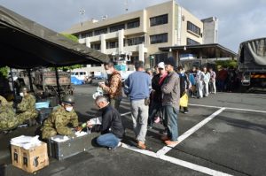 Earthquake-affected evacuees receive rice rations from Japanese Self-Defense Forces personnel at the Mashiki village office in Kumamoto prefecture on April 17, 2016. Rescuers were racing against the weather and the threat of more landslides April 17 to reach people still trapped by two big earthquakes that hit southern Japan. / AFP PHOTO / KAZUHIRO NOGI