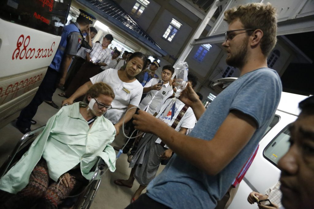 This photo taken late on April 26, 2016 shows German tourist Wiebke Roesler (L), who was injured in a landmine explosion in Myanmar's northeastern Shan State, being accompanied by Felix Zimmerman (R-standing) as she arrives at Mandalay hospital for treatment. The two German tourists were injured in a landmine explosion while visiting a village with a local guide in Shan State, an area rocked by insurgencies over the decades by ethnic minorities fighting for greater autonomy or independence. / AFP PHOTO / STR