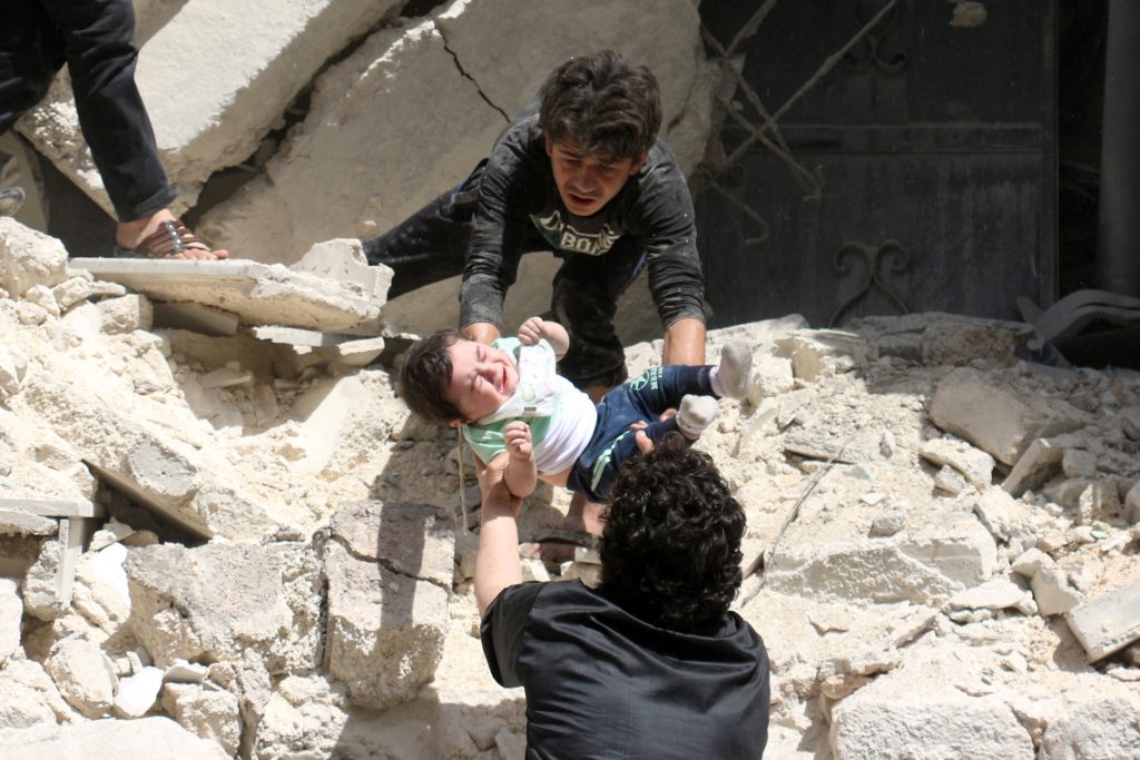 Syrians evacuate a toddler from a destroyed building following a reported air strike on the rebel-held neighbourhood of al-Kalasa in the northern Syrian city of Aleppo, on April 28, 2016. The death toll from an upsurge of fighting in Syria's second city Aleppo rose despite a plea by the UN envoy for the warring sides to respect a February ceasefire. / AFP PHOTO / AMEER ALHALBI