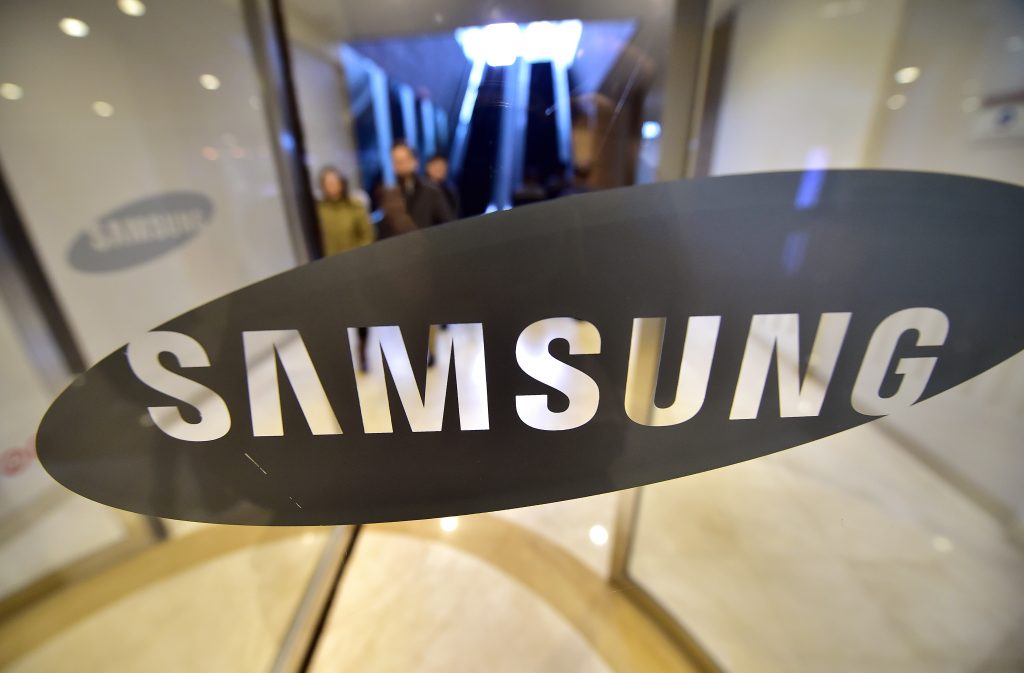 People walk past the logo of Samsung Electronics at the company's headquarters in Seoul on January 28, 2016. Slowing global demand for smartphones as well as memory chips dealt a blow to Samsung Electronics as it reported a 40 percent on-year drop in fourth-quarter net profit.  AFP PHOTO / JUNG YEON-JE / AFP PHOTO / JUNG YEON-JE