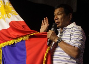 (File Photo) This photo taken on April 19, 2016 shows Rodrigo Duterte, front-runner presidential candidate for the May 9 elections, swearing in front of a national flag and supporters (not pictured) during a campaign sortie in Iloilo City, central Philippines.  AFP PHOTO / STR