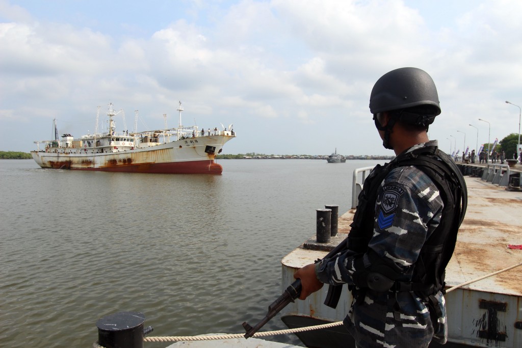 This picture taken on April 23, 2016 shows a member of the Indonesian navy standing before the Chinese trawler "Hua Li-8" (L) in Belawan, North Sumatra. Indonesian warships have detained a Chinese trawler allegedly operating illegally in Indonesian waters, just weeks after a confrontation between vessels from the two countries caused tensions, the navy said on April 24. / AFP PHOTO / ABIMATA HASIBUAN