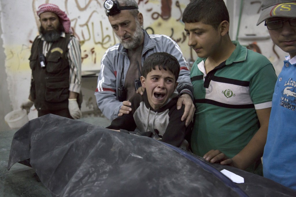 A Syrian boy is comforted as he cries next to the body of a relative who died in a reported airstrike on April 27, 2016 in the rebel-held neighbourhood of al-Soukour in the northern city of Aleppo.  / AFP PHOTO / KARAM AL-MASRI