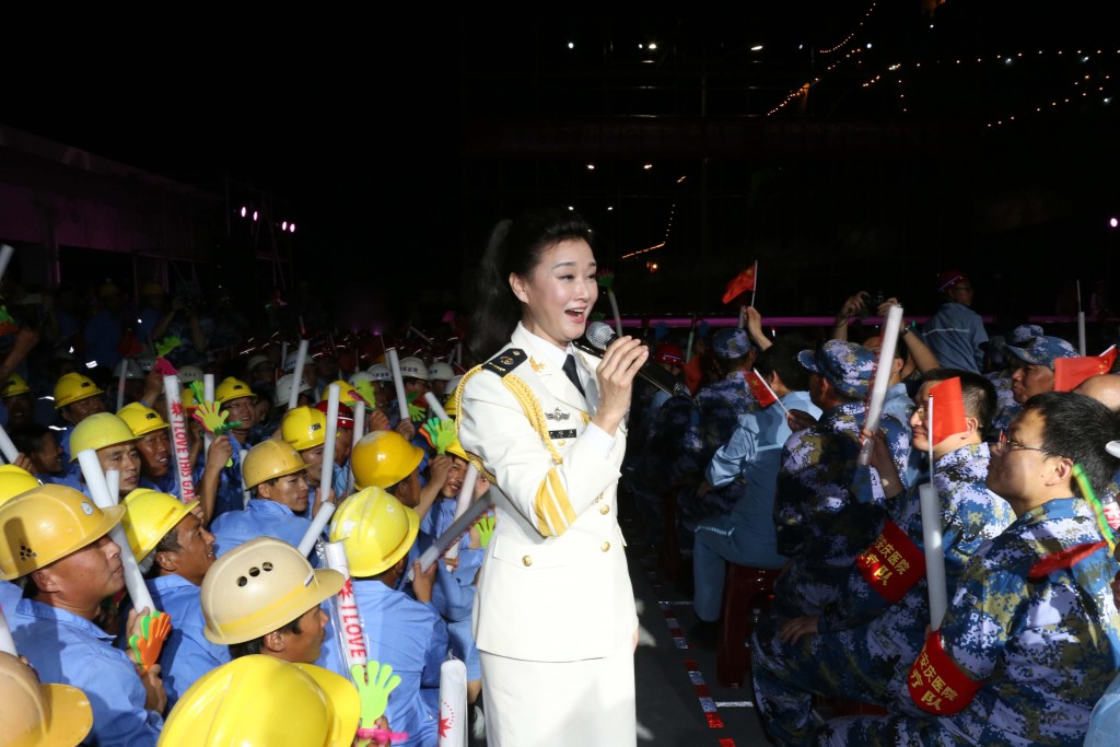 This picture taken on May 2, 2016 shows Chinese folk singer Song Zuying performing for workers and military personnel on Fiery Cross Reef located in the disputed Spratly Islands group in the South China Sea.   One of China's top folk singers is rocking her away across disputed territory in the South China Sea, serenading hundreds of troops and construction workers stationed there, Chinese media reported on May 5. Song Zuying, who has performed with the likes of Canadian superstar Celine Dion, is part of an all-singing, all-dancing People's Liberation Army (PLA) entertainment tour of the Spratly Islands, reports said.  / AFP PHOTO / STR / China OUT