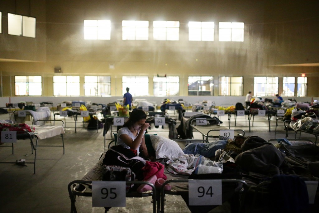 Tyra Abo sits on a cot at a makeshift evacuee center in Lac la Biche, Alberta on May 5, 2016, after fleeing forest fires north of Fort McMurray. Raging wildfires pressed in on the Canadian oil city of Fort McMurray Thursday after more than 80,000 people were forced to flee, abandoning fire-gutted neighborhoods in a chaotic evacuation. No casualties have been reported from the monster blaze, which swept across Alberta's oil sands region driven by strong winds and hot, dry weather.  / AFP PHOTO / Cole Burston