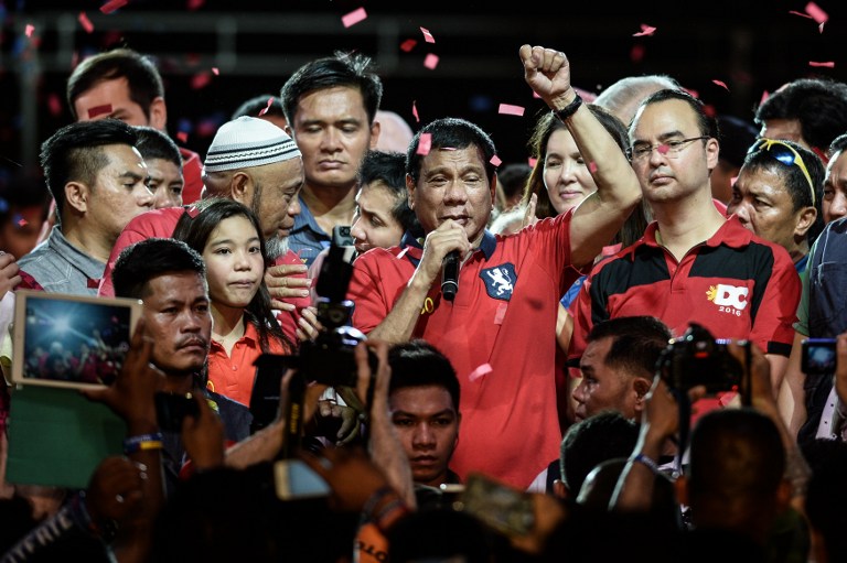 Presidential candidate and Davao Mayor Rodrigo Duterte (C) gestures as he addresses his supporters during an election campaign rally ahead of the presidential and vice presidential elections in Manila on May 7, 2016. Mass murder advocate Rodrigo Duterte heads into May 7's final rallies of an extraordinary Philippine presidential campaign as the shock favourite, but with rivals still having a chance to counter his profanity-laced populist tirades. / AFP PHOTO / MOHD RASFAN