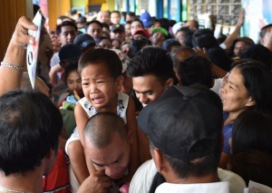 A boy carried by his father cries as they make their way through a crowded polling station as people make their way to cast their ballot in the presidential election in the Quezon City district in suburban Manila on May 9, 2016. The Philippines on May 9 launched elections to elect a new president with anti-establishment firebrand Rodrigo Duterte the shock favourite after an incendiary campaign full of profanity-laced threats to kill criminals. / AFP PHOTO / TED ALJIBE