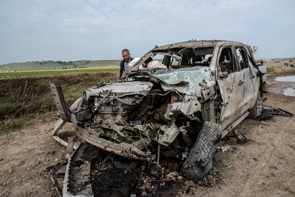 A man walks past a burnt car after a powerful blast on May 13, 2016 in the area of Sarikamis on the outskirts of the majority Kurdish city of Diyarbakir.  A powerful blast that shook an area near the Turkish city of Diyarbakir on May 12 killed four "bombmakers" and injured at least 10 other people, the Interior ministry said. / AFP PHOTO / ILYAS AKENGIN