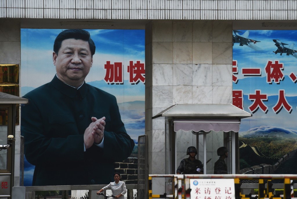 Soldiers stand guard in front of a huge portrait of Chinese President Xi Jinping at the entrance to a military base in Guilin, in China's southern Guangxi region on May 13, 2016. The slogan beside Xi reads "Speed up the establishment of a powerful people's Air Force and sharpen offensive and defensive capabilities". / AFP PHOTO / GREG BAKER