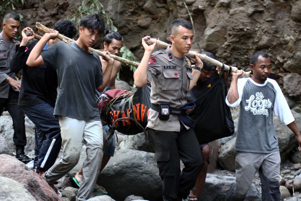 Indonesian police and villagers carry the body of a flash flood victim in Sibolangit, North Sumatra on May 16, 2016. At least eight people were killed and dozens missing May 15 in flash floods that hit the Dua Warna waterfall in Sibolangit where about 80 people were camped, an official said on May 16. / AFP PHOTO / ALBERT DAMANIK