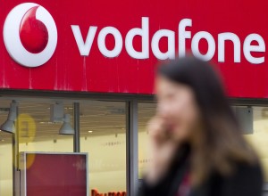 (FILES) This file photo taken on March 17, 2014 shows a woman walking past a branch of Vodafone in London on March 17, 2014.  British telecoms giant Vodafone on May 17, 2016 posted its first annual rise in operating profits in eight years, boosted by growth in Europe and emerging markets. Earnings before interest, tax, depreciation and amortisation (EBITDA) grew 2.7 percent to £11.6 billion ($16.7 billion, 14.7 billion euros) in the year to March, Vodafone said in a results statement. / AFP PHOTO / JUSTIN TALLIS