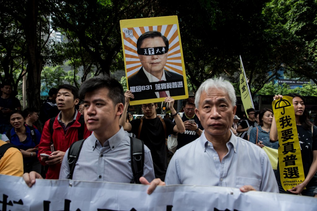 Demonstrators march during a pro-democracy protest in Hong Kong on May 18, 2016, during the second day of a visit by China's National People's Congress (NPC) Standing Committee Chairman Zhang Dejiang (on placard). One of China's most powerful officials arrived in Hong Kong on May 17 in an attempt to build bridges in the divided city, but the trip has already stirred anger among opponents.  / AFP PHOTO / DALE DE LA REY