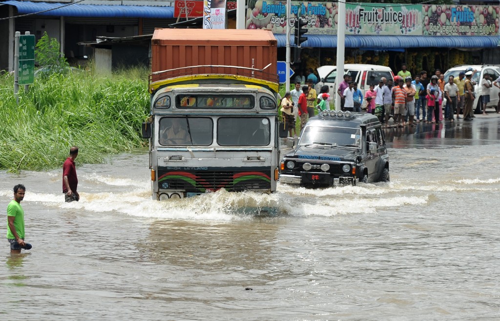 Sri Lankan commuters drive through floodwaters along an expressway in the suburb of Athurugeriya in capital Colombo on May 18, 2016.  Rescue workers in Sri Lanka searched for 16 people missing May 18 after landslides buried several homes following three days of heavy rain, police said.  / AFP PHOTO / LAKRUWAN WANNIARACHCHI