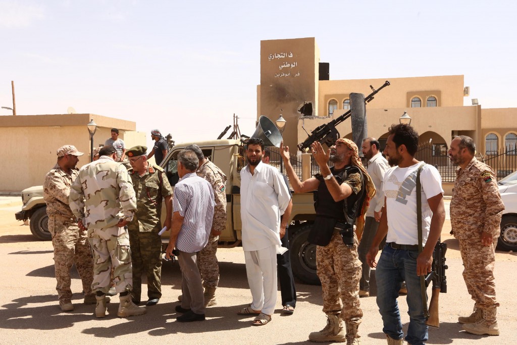 EDITORS NOTE: Graphic content / Libyan pro-government forces celebrate in front of the commercial bank on May 18, 2016 in Abu Grein, south of Libya's third city Misrata, a day after Libya's unity government recaptured the area from the Islamic State (IS) group. four of the Bodies of The organization of the Islamic State (Daash) in a truck in Abu Qurayn About 300 km east of the Libyan capital Tripoli , on May 18, 2016. The UN-backed Government of National Accord (GNA) forces said on Facebook that they recaptured  Abu Grein strategic crossroads, where the coastal highway meets the main road south into the desert interior on May 17, 2016.  / AFP PHOTO / MAHMUD TURKIA