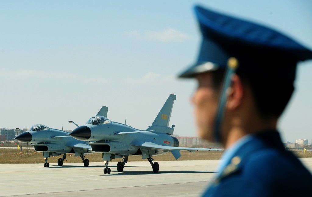 Chinese J-10 fighter jets pass an Air Force officer on the tarmac at the Yangcun Air Force base of the People's Liberation Army Air Force in Tianjin, home of the 24th Fighter Division, southeast of Beijing on April 13, 2010.The base is home to the August 1st (Bayi) Aerobatic Team of the PLAAF, named after the founding of the PLA on August 1, 1927. The Aerobatics team upgraded their jets to the J-10 multirole fighter in May 2009 and military attaches from various countries as well as foreign journalists were invited to the base for the airshow. AFP PHOTO/ Frederic J. BROWN / AFP PHOTO / FREDERIC J. BROWN