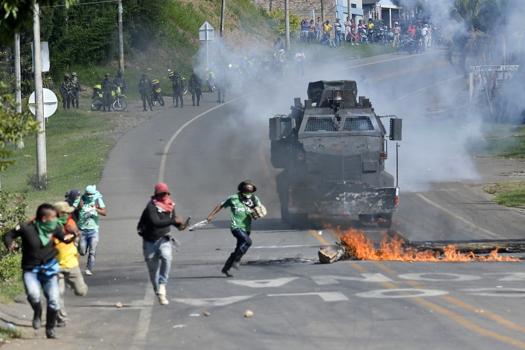 Farmers clash with Colombian riot police as they block the Panamerican highway demanding land reform and increased state spending in rural areas on June 2, 2016, in Pescador, department of Cauca, Colombia. More than 30,000 peasant farmers in Colombia have joined a growing anti-government protest, blocking roads and engaging in clashes with police that have wounded 28 people, officials said Thursday. / AFP PHOTO / LUIS ROBAYO