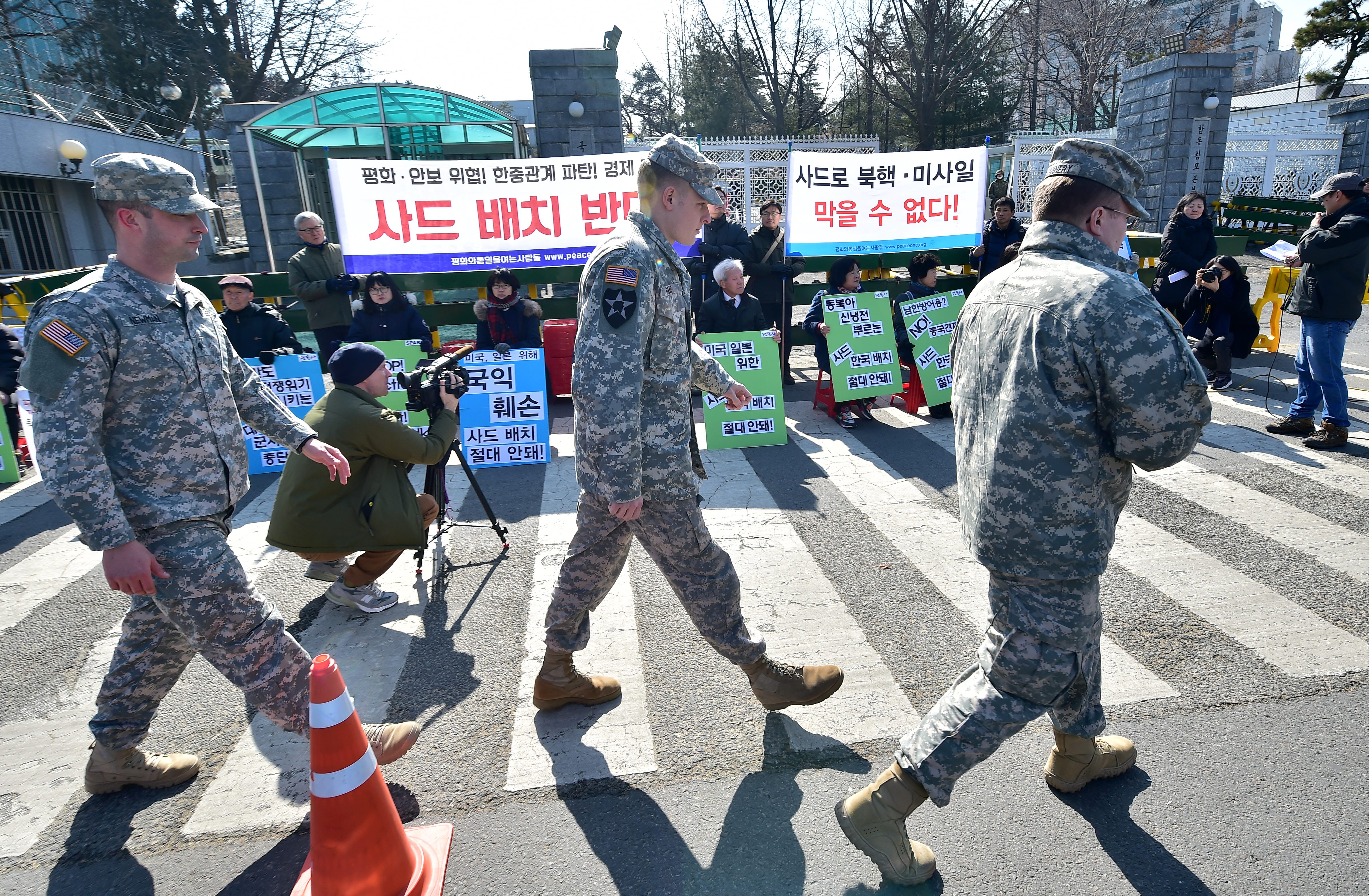 US soldiers walk past South Korean anti-war activists holding a rally against talks on deploying the Terminal High Altitude Area Defence System (THAAD) outside the Defence Ministry in Seoul on February 23, 2016. Washington and Seoul have postponed talks on deploying an advanced missile defence system opposed by Beijing, South Korea's defence ministry said as China's foreign minister was set to discuss North Korea with his US counterpart. AFP PHOTO / JUNG YEON-JE / AFP PHOTO / JUNG YEON-JE