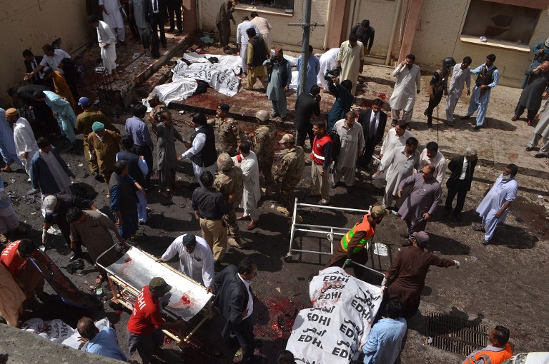 Pakistani security officials and lawyers gather around the bodies of victims killed in a bomb explosion at a government hospital premises in Quetta on August 8, 2016. At least 40 people were killed and dozens more wounded after a blast at a major hospital in the Pakistani city of Quetta, the provincial health minister said, with fears the toll will rise. / AFP PHOTO / BANARAS KHAN