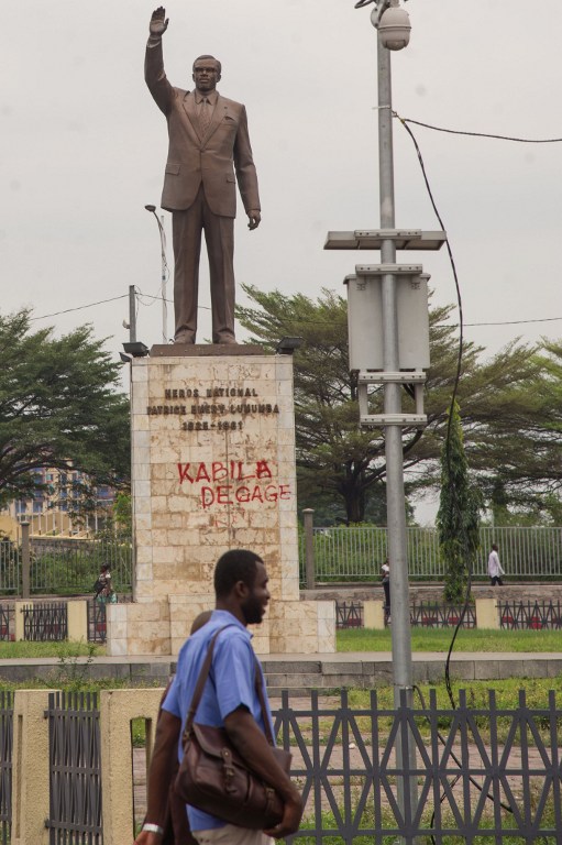 A man walks past a statue with a graffiti reading "Kabila get out" in Kinshasa on September 21, 2016, following two days of clashes. Two days of clashes in the Democratic Republic of Congo's capital Kinshasa, that pitted the security forces against protesters who demanded President Joseph Kabila's resignation, left at least 32 people dead, police said today. During the clashes, a police station and 12 other police positions were looted and set on fire on September 20, the spokesman said, branding the rioters "insurgents".  / AFP PHOTO / Junior KANNAH