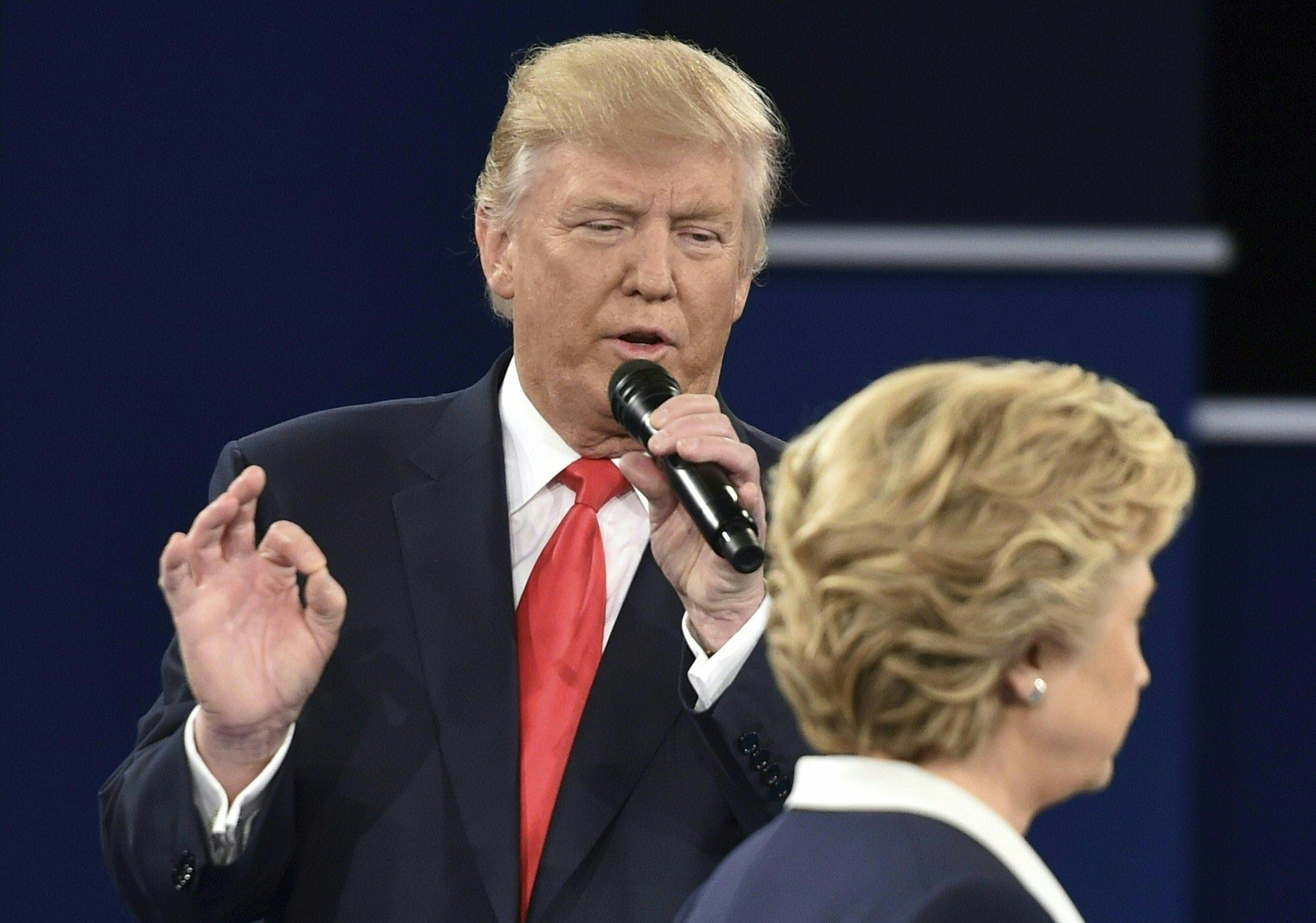 Republican presidential candidate Donald Trump speaks as Democratic presidential candidate Hillary Clinton walks past during the second presidential debate at Washington University in St. Louis, Missouri on October 9, 2016. / AFP PHOTO / Paul J. Richards