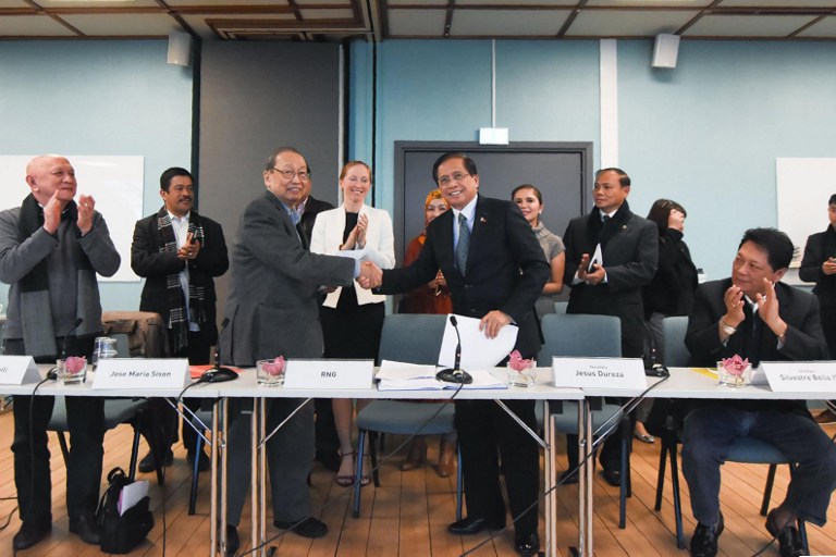 This handout photo taken on October 9, 2016 and released on October 10 by the Office of the Presidential Adviser on Peace Process (OPAPP) shows Philippine Secretary for the Peace Process Jesus Dureza (center R) shaking hands with chief political consultant of the communist party Jose Maria Sison (center L) after signing a joint statement during the second round of peace talks in Oslo, Norway, while the chief of National Democratic Front Peace Panel (NDFP) Fidel Agcaoili (L) and his government counterpart Silvestre Bello (R) applaud. Hundreds of detained communist rebels in the Philippines are likely to be granted amnesty, officials said October 10, after fresh peace talks aimed at ending one of Asia's longest-running insurgencies. / AFP PHOTO / OPAPP / STR /