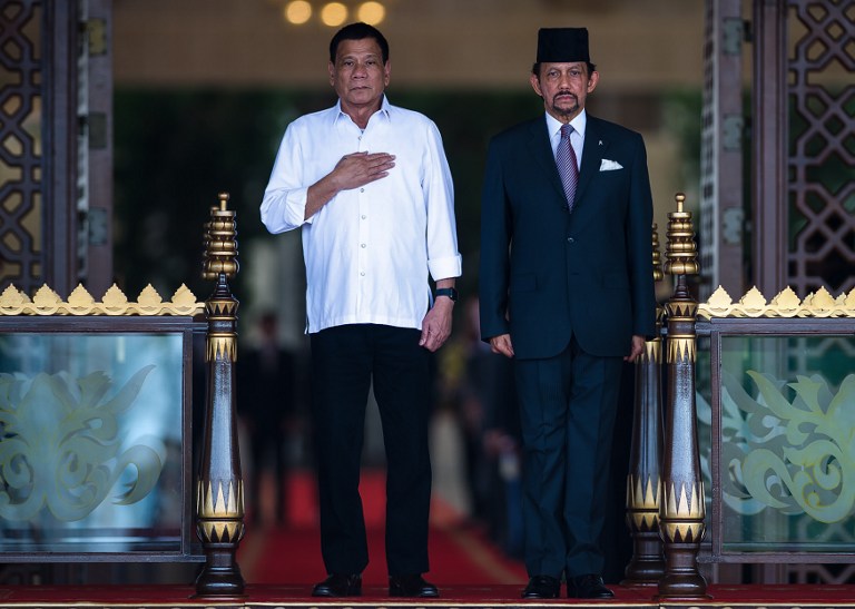 In this handout photograph released on October 17, 2016 by the Brunei Information Department, Brunei's Sultan Hassanal Bolkiah (R) and Philippine's President Rodrigo Duterte (L) stand for national anthems of both nations during Duterte's official welcoming ceremony at the Istana Nurul Iman in Brunei Darussalam. --- "AFP PHOTO / BRUNEI INFORMATION DEPARTMENT" /AFP PHOTO / Brunei Informations Department / Brunei Information Department