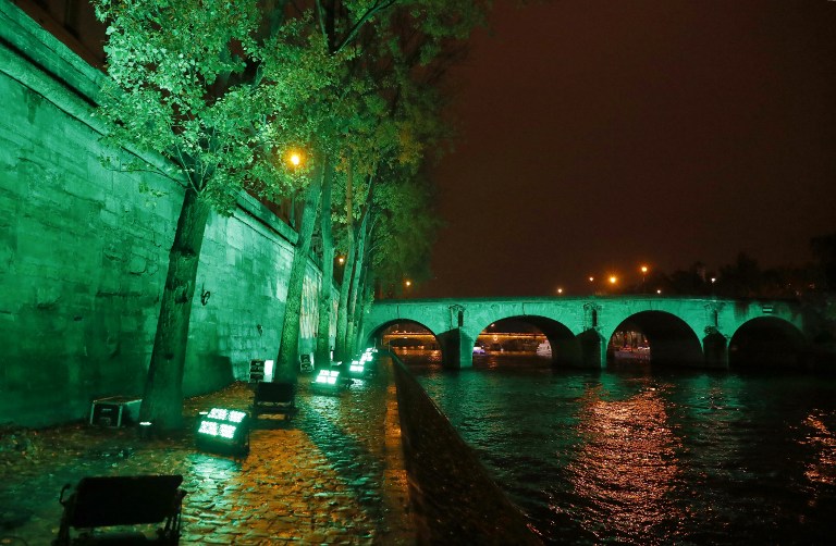 The Pont Marie bridge and the bank of the Seine River are illuminated in Paris on November 4, 2016, to celebrate the first day of the application of the Paris COP21 climate accord. The worldwide pact to battle global warming entered into force on November 4, just a week before nations reassemble to discuss how to make good on their promises to cut planet-warming greenhouse gases. Dubbed the Paris Agreement, it is the first-ever deal binding all the world's nations, rich and poor, to a commitment to cap global warming caused mainly by the burning of coal, oil and gas. / AFP PHOTO / PATRICK KOVARIK