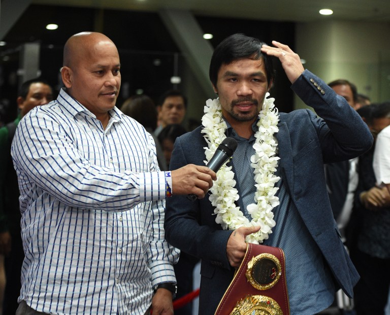 Philippine boxing icon Manny Pacquiao (R) shows members of the media the stiches on his head as a result of his boxing bout with Mexican boxer Jesse Vargas, upon arriving at Manila airport on November 8, 2016, while national police chief Ronald Dela Rosa holds the microphone. / AFP PHOTO / TED ALJIBE