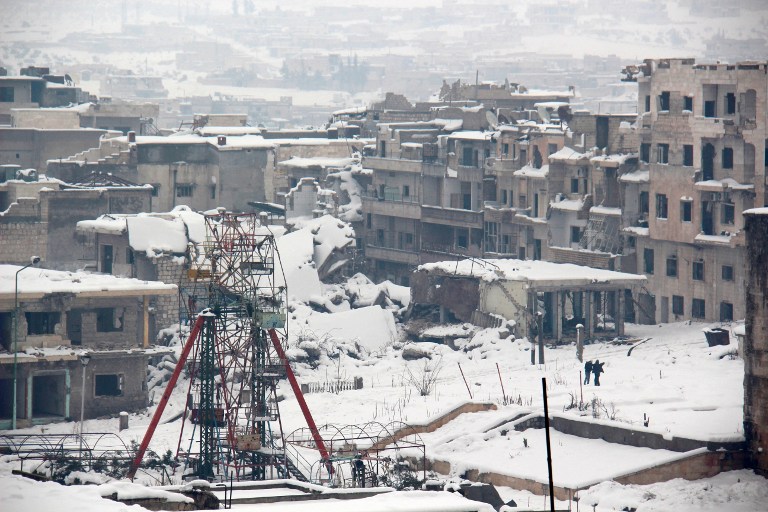 Syrians walk in a snow covered street in the town of Maaret al-Numan, in Syria's northern province of Idlib, on December 22, 2016. Rebels and civilians who have sought refuge in the opposition-held province of Idlib, most recently from second city Aleppo, say they are suffering from skyrocketing prices and overpopulation. At least 25,000 people, including rebel fighters, have left east Aleppo since last week under an evacuation deal that will see the city come under full government control. / AFP PHOTO / AL-MAARRA TODAY / GHAITH OMRAN