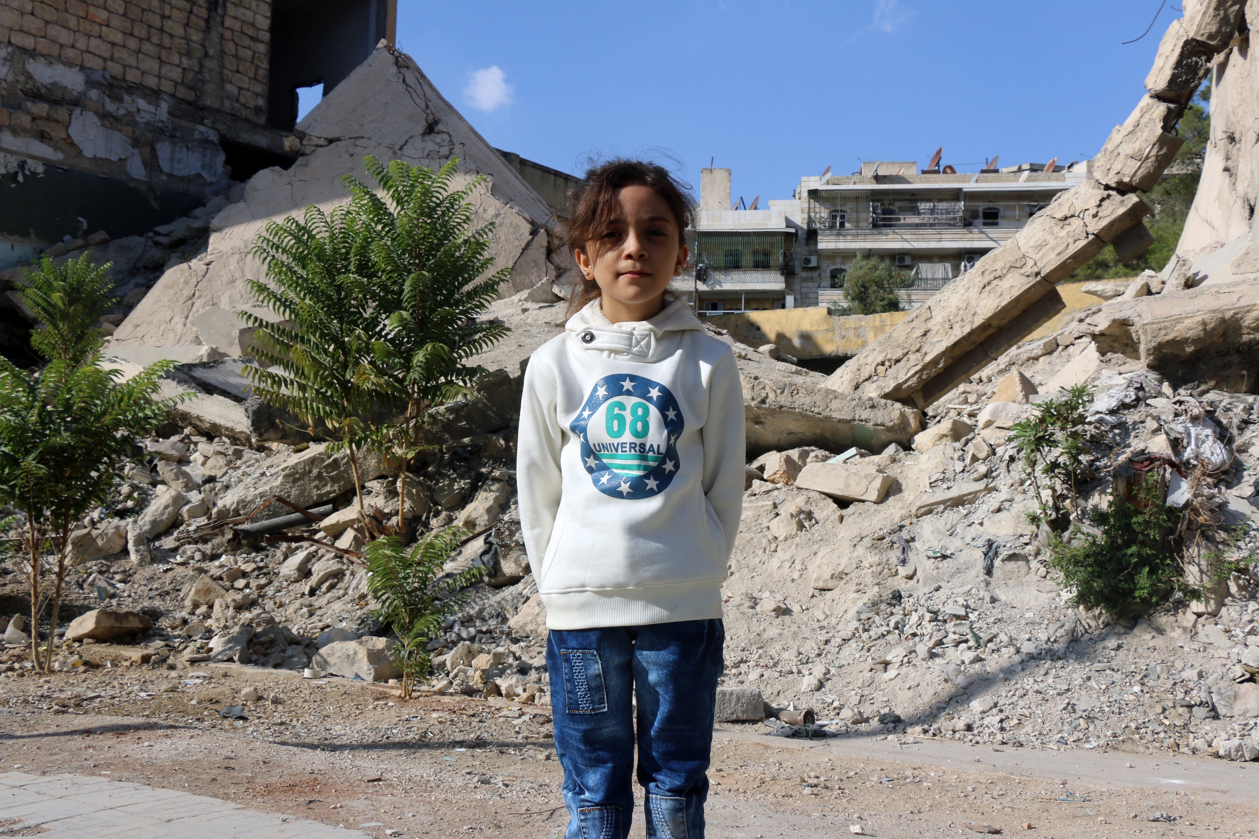 Syrian Bana al-Abed, who with the help of her mother had been posting heartrending tweets in English on life in the besieged eastern districts of Syria's Aleppo, poses for a picture amid the rubble of a destroyed building in east Aleppo on October 10, 2016. The seven-year-old Syrian girl whose Twitter account from Aleppo gained international attention has fled her home amid heavy fighting, but she and her family are safe for now, her father said on December 6, 2016.  / AFP PHOTO / THAER MOHAMMED