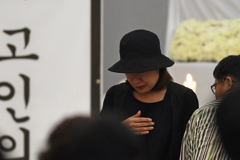 Choi Kyung-Jin (C), widow of late South Korean businessman Jee Ick-Joo who was allegedly killed by suspected policemen, walks towards her seat after offering prayers during a memorial service for her late husband at the police national headquarters in Manila on February 6, 2017.  The South Korean businessman was allegedly kidnapped by Philippine policemen under the guise of a raid on illegal drugs and murdered at the national police headquarters in Manila, authorities said on January 18. / AFP PHOTO / TED ALJIBE