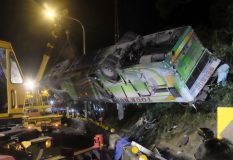 A bus that crashed along a highway is lifted by cranes in Taipei on February 14, 2017.  A bus in Taiwan reported to have been taking local tourists home from visiting seasonal cherry blossoms veered off a highway with 32 feared dead, the national fire department said. / AFP PHOTO / SAM YEH