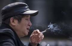 In this photo taken on February 28, 2017, a man smokes a cigarette on the streets in Shanghai.   Shanghai widened its ban on public smoking March 1 as China's biggest city steps up efforts to stub out the massive health threat despite conflicts of interest with the state-owned tobacco industry.  / AFP PHOTO / Johannes EISELE