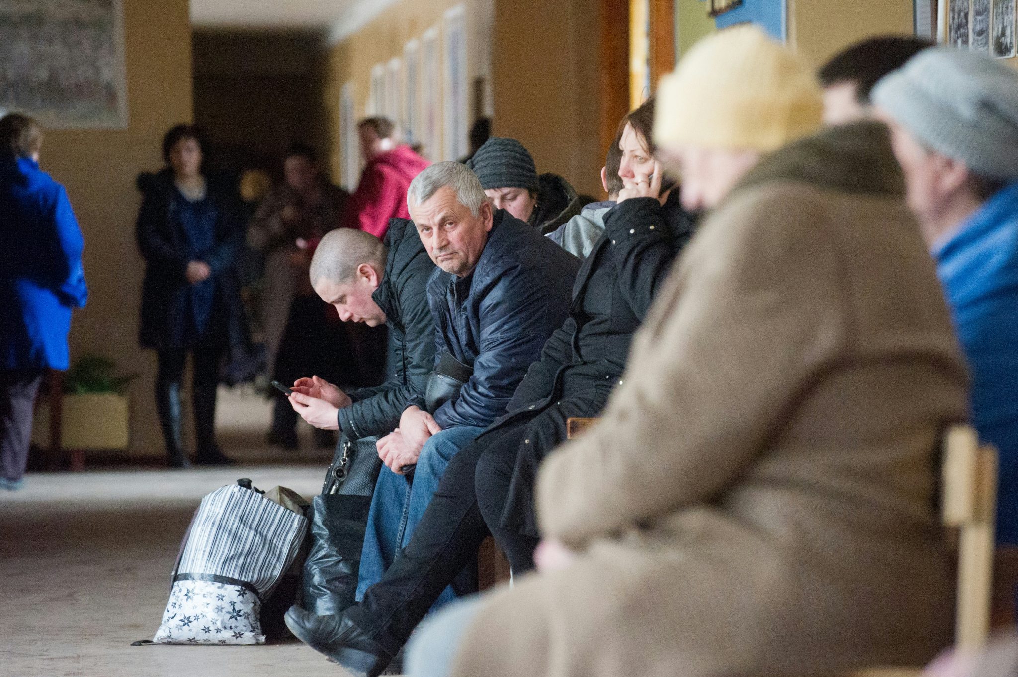 People, who were evacuated due to a fire raging at a military munitions depot near the city of Balakliya, wait on March 23, 2017 at a school in the village of Savintsy in the Kharkiv province of eastern Ukraine. Ukraine said that a fire raging at a munitions depot (caused by a series of explosions) in the country's east, which the military blamed on an "act of sabotage", could continue for up to a week. "We can evaluate everything as the intensity of the fire decreases," Ukrainian Prime Minister said in televised comments. / AFP PHOTO / SERGEY BOBOK