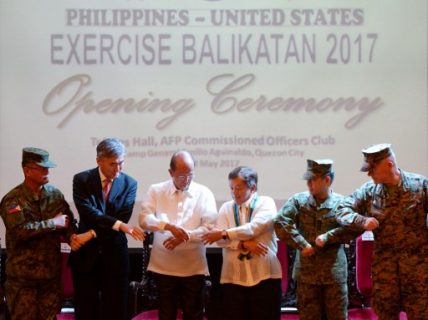 From L-R: Philippine exercise director Lieutenant General Oscar Lactao, US Ambassador to the Philippines Sung Kim, Philippine Defence Minister Delfin Lorenzana, Philippine Foreign Affairs Under Secretary Ariel Abadilla, Philippine military chief Eduardo Ano, and US exercise director Lieutenant General Lawrence Nicholson link arms during the opening of the annual Philippines-US military exercise at Camp Aguinaldo, Quezon City, suburban Manila on May 8, 2017.  The Philippines and United States launched annual military exercises in Manila on May 8 but the longtime allies scaled them down in line with President Rodrigo Duterte's pivot to China and Russia. / AFP PHOTO / TED ALJIBE