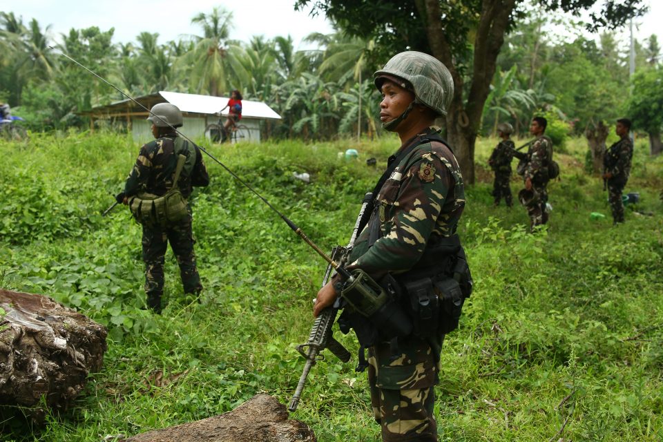 This photo taken on May 10, 2017 shows Philippine soldiers patrolling along a village near a highway in Maguindanao province, in southern island of Mindanao, after almost a week of attacks on members of the Bangsamoro Islamic Freedom Fighters (BIFF). More than 24,000 people fled their homes as the Philippine military used airstrikes and artillery against Muslim extremists who have pledged allegiance to the Islamic State, authorities said May 11. / AFP PHOTO / FERDINANDH CABRERA