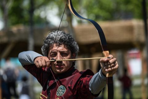 An archer wearing an ottoman costume aims at a target on May 11, 2017, during an oil wrestling tournament at part of "Ethnosports Culture Festival" in Istanbul. Some 800 athletes gathered in Istanbul for the "Ethnosports Culture Festival" aimed at promoting ancient Turkish sports, including Ottoman archery, horse riding and oil wrestling. / AFP PHOTO / OZAN KOSE