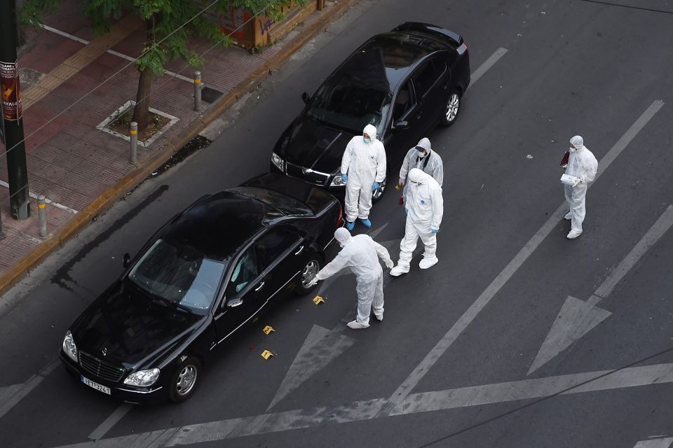 Forensic experts of the police search for evidence in and around the car of Greek former prime minister Lucas Papademos in Athens on May 25, 2017, after Papademos was hurt when an explosive device went off inside his car. State news agency ANA said Papademos was undergoing surgery for abdominal and leg injuries at an Athens hospital. State TV ERT earlier reported that he also had trouble breathing, but his life was not in danger. / AFP PHOTO / Eleftherios ELIS